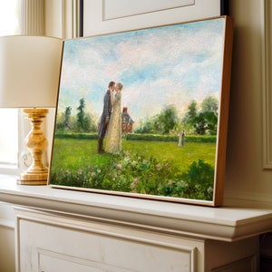 Puede incluir: Una pintura al &oacute;leo enmarcada representa a una pareja bes&aacute;ndose en un jard&iacute;n. La obra de arte presenta un cielo azul claro, hierba verde y una casa de ladrillo rojo en el fondo. La pintura se exhibe sobre una repisa blanca, junto a una l&aacute;mpara dorada.