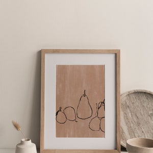 May include: A framed print of a minimalist line drawing of pears on a light brown background. The frame is made of light wood.