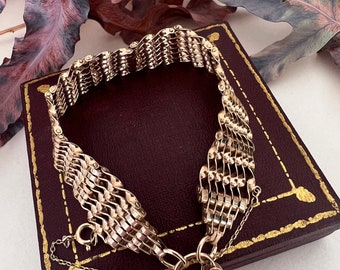 May include: A gold chain bracelet with a heart-shaped padlock clasp. The bracelet is on a burgundy velvet box.