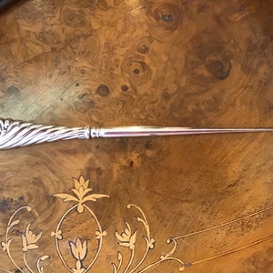 Peut inclure: Un enfile-aiguille en argent avec une poignée torsadée décorative et un crochet à l'extrémité.