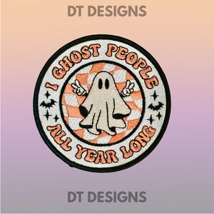 May include: Embroidered patch with a black border featuring a ghost illustration with peace signs. The patch has the text "I GHOST PEOPLE ALL YEAR LONG" in orange lettering. The background is a white and orange checkered pattern.