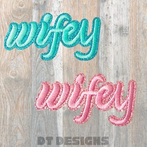 May include: Two embroidered patches with the word "wifey". One is teal with a glittery border, the other is pink with a glittery border. The patches are on a wooden background.