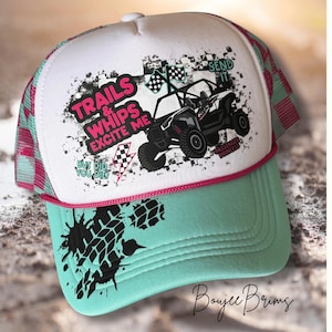 May include: A white trucker hat with a teal brim and pink mesh backing. The hat features a graphic of an off-road vehicle and the text "Trails & Whips Excite Me" and "Send It". The hat also has the text "Passenger Princess" and "But Did You Die?"