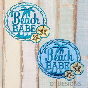 May include: Two embroidered patches with a beach theme. Each patch features the words "Beach Babe" in blue script, a palm tree, and a sand dollar design. The patches are circular with a rope-like border.