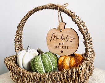 May include: A wicker basket filled with three small pumpkins. A wooden pumpkin-shaped tag is attached to the basket handle with the text "Mabel's Boo Basket"