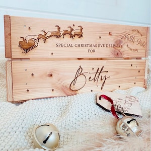 Puede incluir: Una caja de madera con un tema de entrega de Nochebuena. La caja está decorada con un diseño de renos y trineo y el texto "Special Christmas Eve Delivery for Betty". La caja también tiene una pequeña etiqueta de madera con el texto "This Magic Key to Christmas".