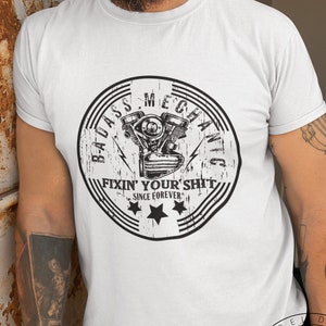 May include: White t-shirt with a black and white graphic of a motorcycle engine with the text "Badass Mechanic Fixin' Your Shit Since Forever."