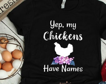 Könnte beinhalten: Schwarzes T-Shirt mit weißem Text, der "Yep, my Chickens Have Names" lautet. Unter dem Text befindet sich eine weiße Silhouette eines Huhns mit lila Blumen.