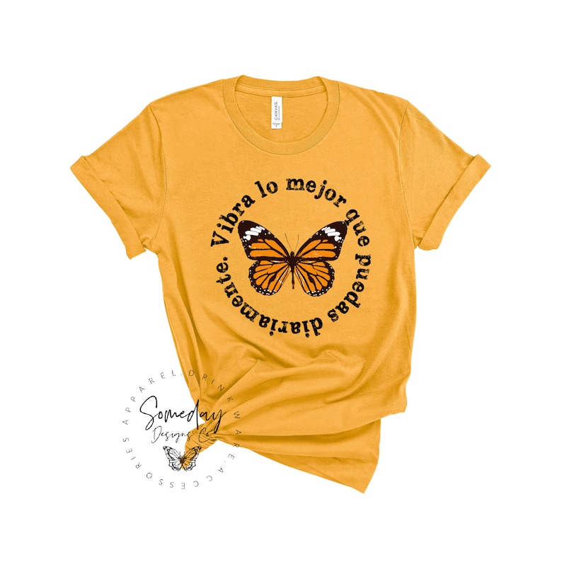K&ouml;nnte beinhalten: Gelbes T-Shirt mit einem schwarzen Kreis-Motiv mit einem Schmetterling und dem Text "Vibra lo mejor que puedas diariamente."