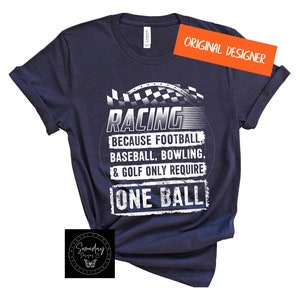 Op de afbeelding: Een marineblauw t-shirt met een witte afbeelding waarop staat "RACING because football, baseball, bowling, & golf only require ONE BALL".