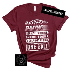 Op de afbeelding: Bordeauxkleurig T-shirt met een witte afbeelding met de tekst "RACING because FOOTBALL, BASEBALL, BOWLING, & GOLF only require ONE BALL".