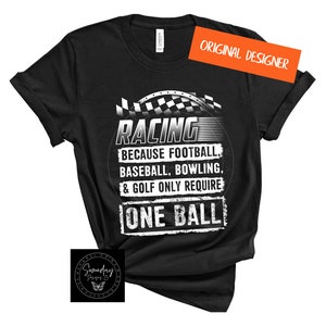 Op de afbeelding: Zwart T-shirt met een witte afbeelding waarop staat "RACING because football, baseball, bowling, & golf only require ONE BALL". De afbeelding bevat ook een geruit vlagontwerp.