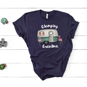 May include: Navy blue t-shirt with a white camper van and pink flamingos graphic. The text "Glamping Grandma" is printed below the camper van.