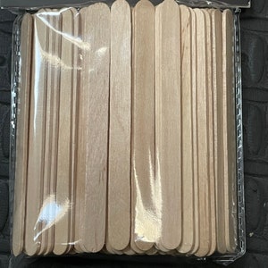 May include: A pack of wooden craft sticks, approximately 50 sticks, in a clear plastic bag. The sticks are all the same size and are arranged in a neat, even row.