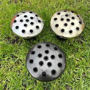 May include: Three metal flower frog vases. Two are silver and one is black. Each vase has a circular top with multiple holes for flower stems.