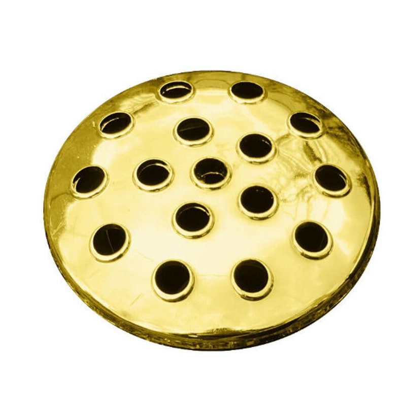 Puede incluir: Una base de arreglo floral de metal dorado con m&uacute;ltiples agujeros redondos para sujetar tallos.