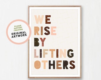 May include: A motivational poster with the text "We Rise By Lifting Others" in colorful, layered letters on a beige background.