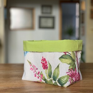 May include: A green and white floral fabric storage basket with a green fabric top.