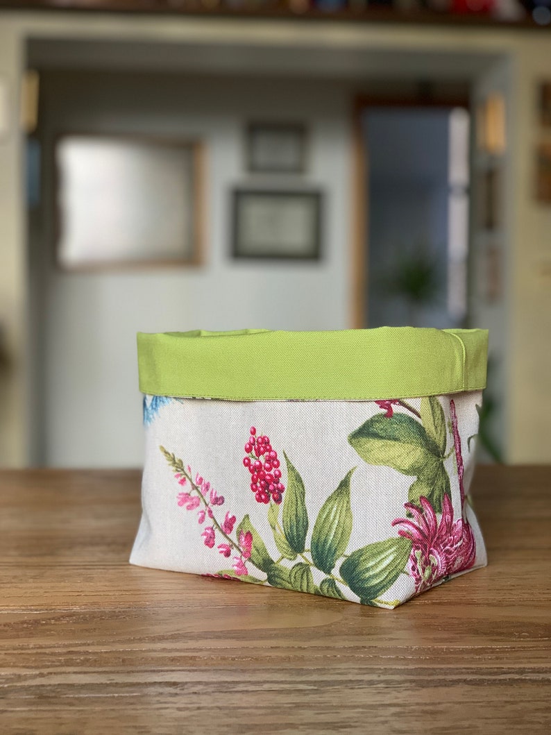 May include: A green and white floral fabric storage basket with a green fabric top.