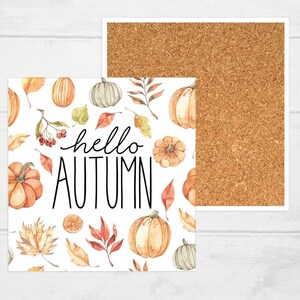 May include: White coaster featuring a watercolour design of pumpkins, leaves, and berries. The text "hello autumn" is written in black cursive.