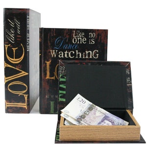 May include: Three decorative book-shaped boxes with hidden compartments. The boxes are black with gold and colorful text. The text on the boxes reads "LOVE like it will NEVER HURT", "Like no one is Dance Watching", and "Like no".