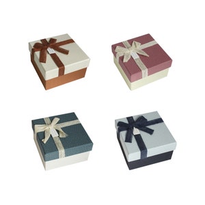 May include: Four gift boxes with different colored lids and bows. The boxes are all the same size and shape. The lids are brown, pink, blue, and black. The bows are all made of white ribbon.