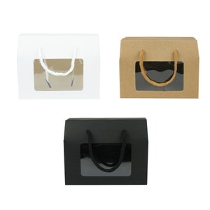 May include: Three gift boxes with a window and a rope handle. The boxes are white, brown, and black.