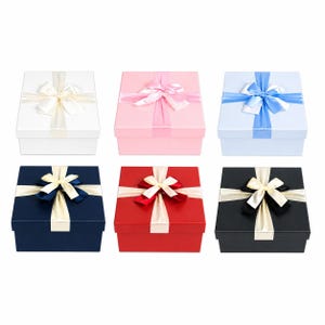 May include: Six square gift boxes in various colors: white, pink, light blue, navy, red, and black. Each box is adorned with a matching ribbon and a contrasting satin bow. The boxes are arranged in a grid pattern.