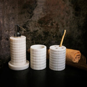 Può includere: Set da bagno in marmo bianco con dispenser di sapone, porta spazzolini da denti e bicchiere. Il set presenta un motivo a piastrelle quadrate.