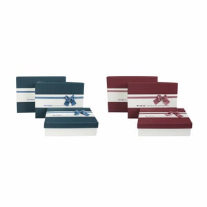 May include: Three gift boxes with blue and red lids and white bases. The boxes have a white ribbon with the word "Wishes" printed on them. The boxes are decorated with blue and pink bows.