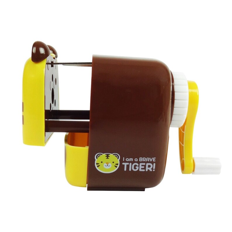 Pode incluir: Um apontador de l&aacute;pis marrom e amarelo com um design de rosto de tigre. O apontador tem uma manivela e uma gaveta para coletar as aparas de l&aacute;pis. O texto "I am a BRAVE TIGER!" est&aacute; impresso no lado.