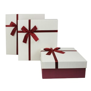 May include: Three gift boxes with white lids and red ribbon bows. The smallest box has a burgundy base.
