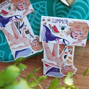 Könnte beinhalten: Zwei Sätze bunter Aufkleber mit einer Comicfigur mit blonden Haaren und blauen Augen. Die Aufkleber befinden sich auf einer durchsichtigen Plastikfolie und tragen die Aufschrift "Summer Verano".