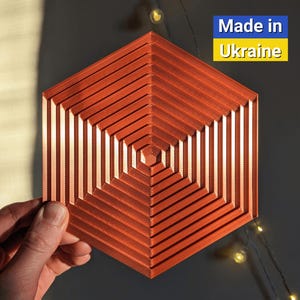 May include: A hexagonal, geometric, orange-colored, 3D printed wall decor with a concentric pattern of lines. The text "Made in Ukraine" is visible in the upper right corner of the image.