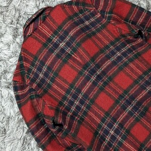 May include: A red and black plaid flannel shirt. The shirt features a classic plaid pattern with green and navy blue accents. The fabric appears to be a soft, woven material, and the shirt is folded.
