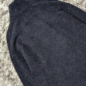 May include: A navy blue fleece jacket with a high collar. The jacket has a soft, textured appearance. The image is a close-up of the jacket, showing the details of the fabric.