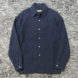 May include: A navy blue button-down shirt with a small white polka dot pattern. The long-sleeved shirt has a classic collar and buttoned cuffs. The shirt is made of a soft, woven fabric.