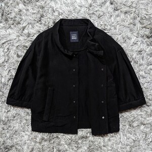 May include: A black button-down jacket with a textured fabric, featuring three-quarter length sleeves, a stand-up collar, and a front placket with visible buttons. A small rectangular label with the text LIMI feu is sewn inside the neckline.