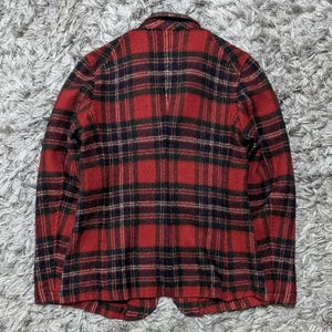 May include: A red and black plaid blazer. The jacket has a classic plaid pattern with a mix of red, black, and green. The blazer has a notched collar and two front pockets. The fabric appears to be a wool blend.