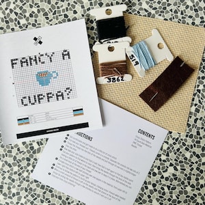 Puede incluir: Kit de punto de cruz con el texto "FANCY A CUPPA?". Incluye un patrón impreso, hilos negro, marrón y azul, una aguja y tela Aida. Ideal para aficionados al bordado y manualidades.