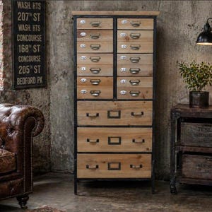 May include: A tall wooden apothecary chest featuring a black metal frame, twelve small upper drawers labelled with letters A through N, and three large lower drawers, each equipped with dark metal pull handles and label holders.