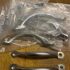 May include: A selection of silver cabinet handles and screws. The handles are in different shapes, including curved and straight designs. The hardware is packaged in clear plastic.