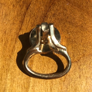 May include: A gold-toned metal ring pull cabinet knob with a circular base and a ring-shaped handle.