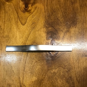 May include: A silver metal cabinet pull with a curved design.