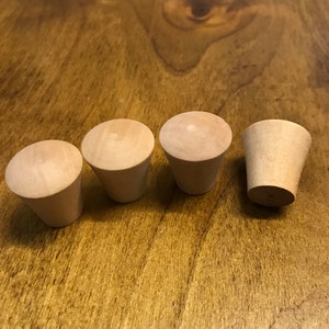 May include: Four wooden knobs, three round and one cone-shaped, on a wooden surface.