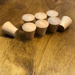 May include: Ten wooden knobs in a light brown colour. The knobs are cone-shaped and have a smooth finish.