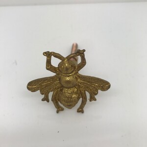 May include: A gold bee-shaped cabinet knob with a detailed design.