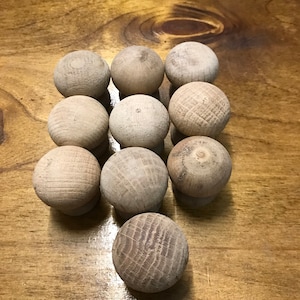 May include: A group of 10 wooden knobs in various shades of brown, arranged in a pyramid shape on a wooden surface.