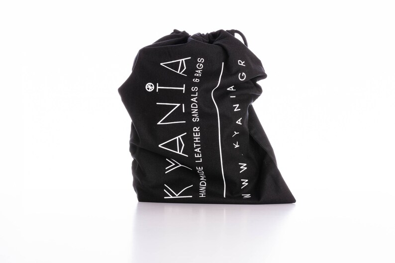 May include: Black drawstring bag with white text that reads "KYANIA HANDMADE LEATHER SANDALS & BAGS WWW.KYANIA.GR"