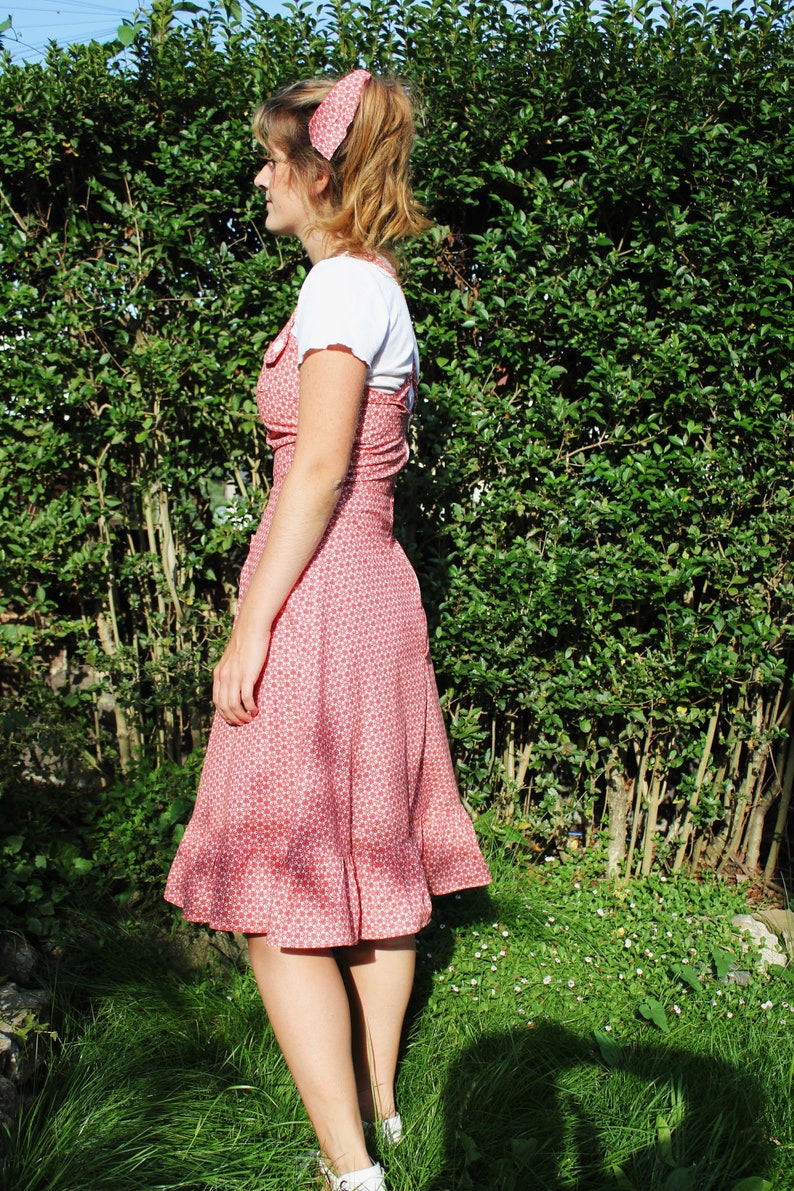 The ROBYN Pinafore Handmade pinafore dress in red floral fabric with cross back straps ruffle hem and pockets